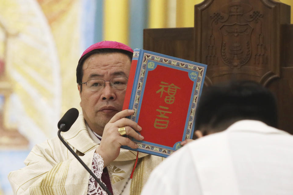 CORRECTS THE DATE IN THE SECOND REFERENCE TO NOV. 14 - FILE - Chinese Bishop Joseph Li Shan holds up a holy Bible as he leads the Christmas Eve mass at the Xishiku Catholic Church in Beijing, China, on Dec. 24, 2018. The head of the Catholic church in China began a trip to Hong Kong on Tuesday, Nov. 14, 2023, at the invitation of the city’s pope-appointed Roman Catholic cardinal, marking the first official visit by a Beijing bishop in history. (AP Photo/Ng Han Guan, File)