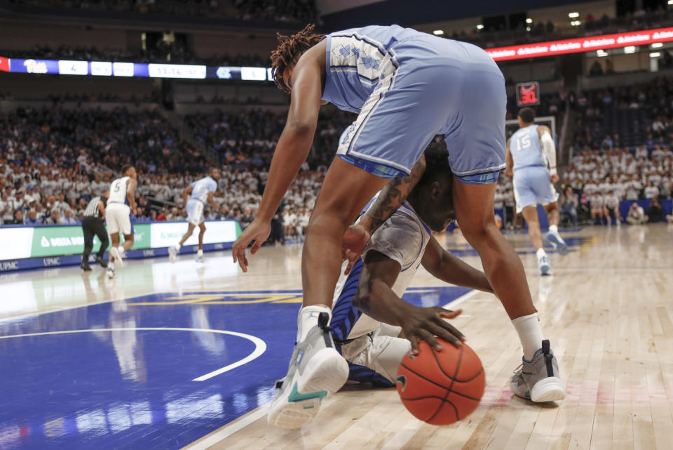 Pittsburgh's Eric Hamilton, bottom, dives for a loose ball under North Carolina's Armando Bacot during the first half of an NCAA college basketball game, Saturday, Jan. 18, 2020, in Pittsburgh. (AP Photo/Keith Srakocic)