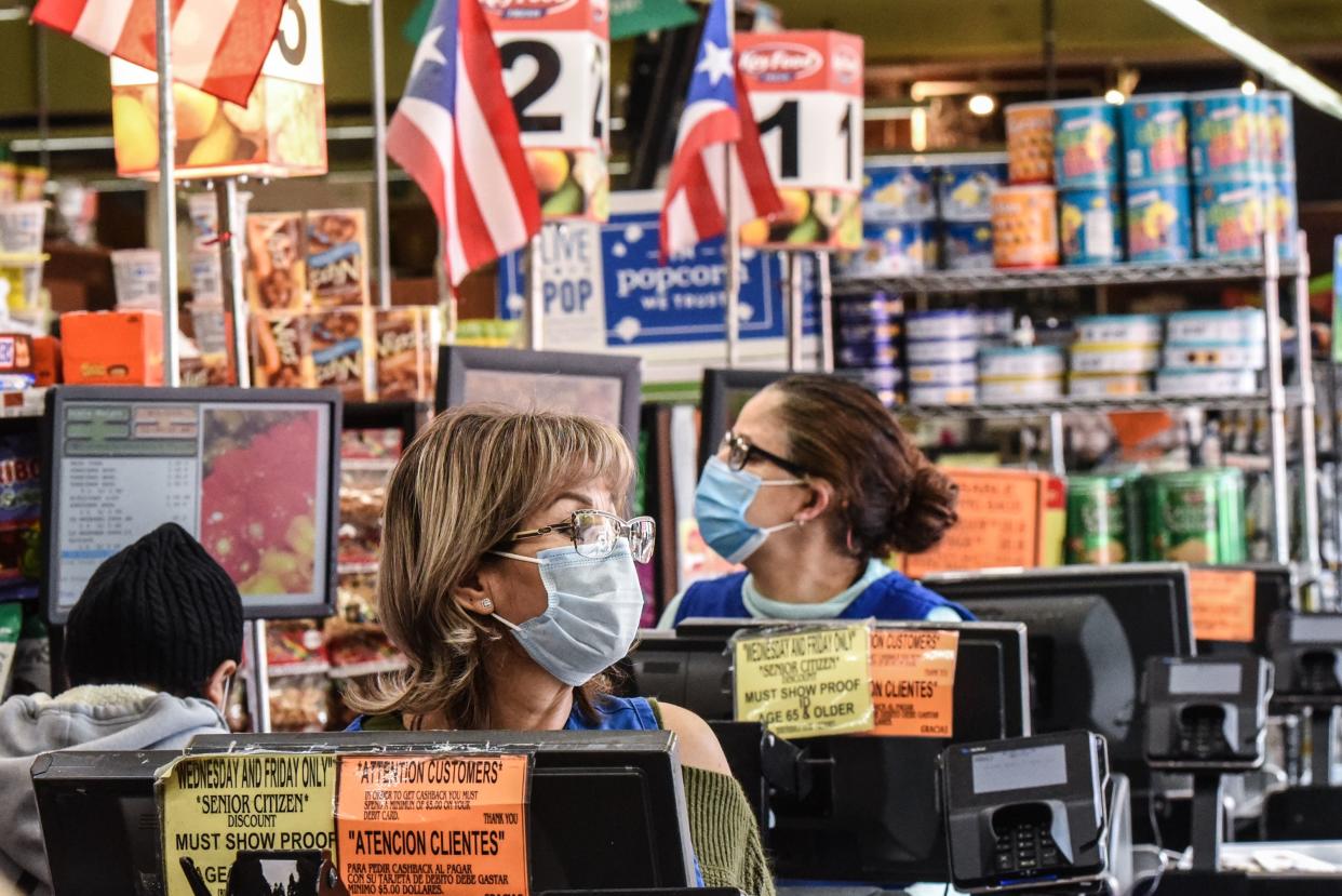 Cashiers wearing protective masks work in a grocery store in the Bushwick neighborhood of Brooklyn on April 2, 2020 in New York City.