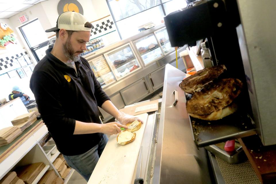 Bagel Masters owner Matt Cottrell spreads cream cheese on a bagel at the Shrewsbury shop Wednesday, April 19, 2023.