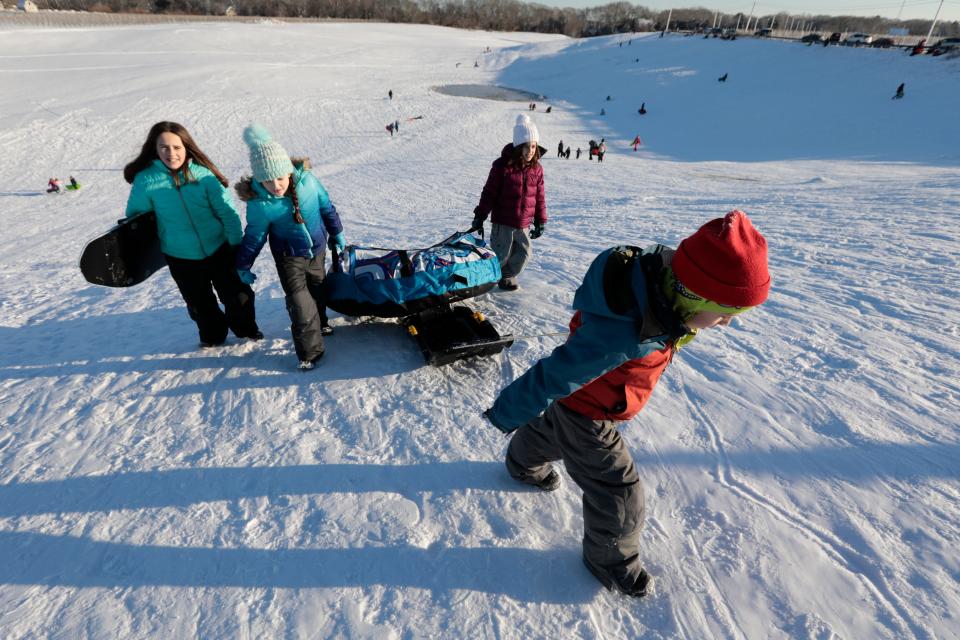 Sledders drag their rides back up the hill during a session of sledding at Potato Hill in Westport.