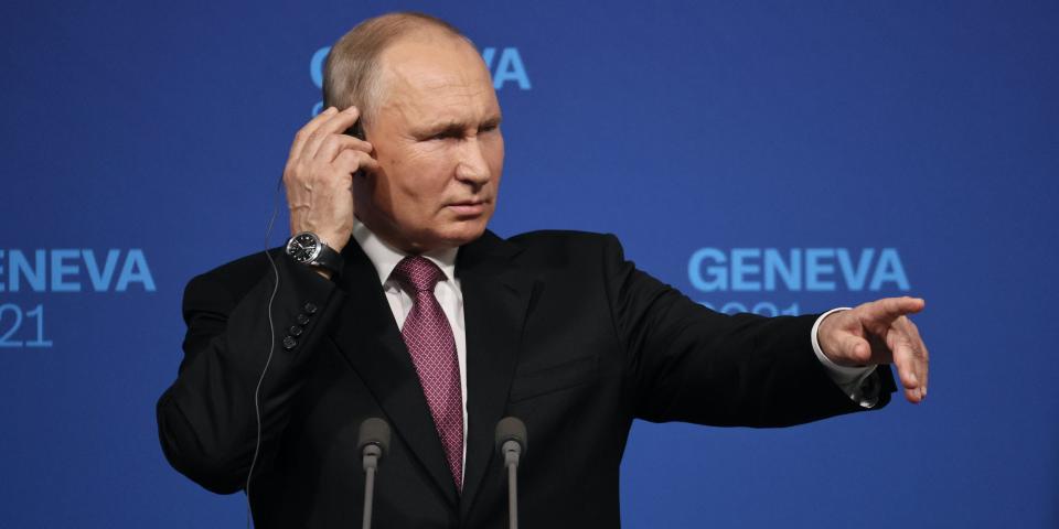 Russian President Vladimir Putin holds his earpiece while listening to a translation of a question from an American reporter at a news conference.