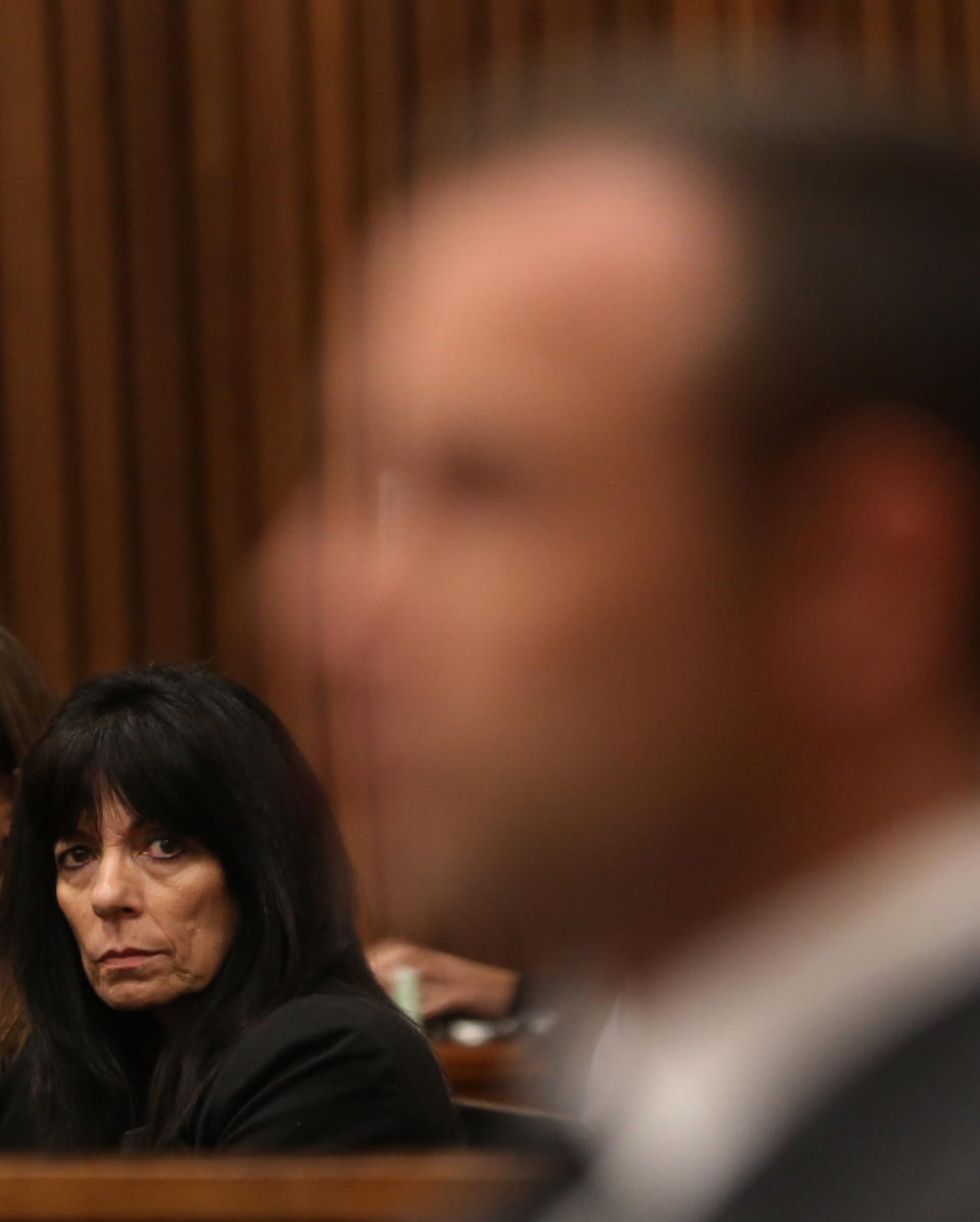 An Unidentified family friend of Reeva Steenkamp glances at Oscar Pistorius, foreground, during his trial at the high court in Pretoria, South Africa, Friday, March 7, 2014. Pistorius is charged with murder for the shooting death of his girlfriend, Steenkamp, on Valentines Day in 2013. (AP Photo/Themba Hadebe, Pool)