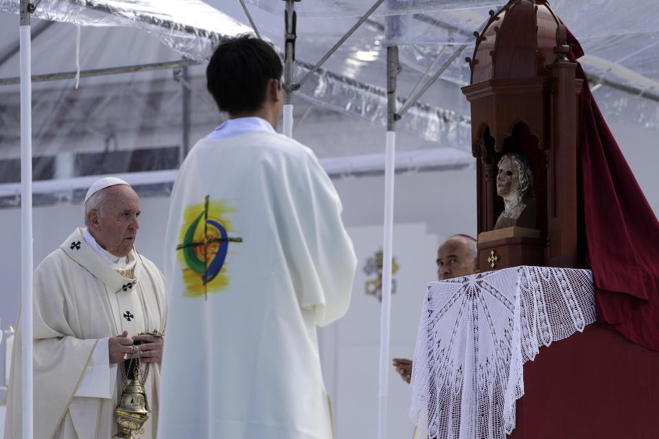 Pope Francis, left, looks at a statue damaged by the 1945 atomic bombing in Nagasaki during a Mass at a baseball stadium Sunday, Nov. 24, 2019, in Nagasaki, Japan. (AP Photo/Gregorio Borgia)