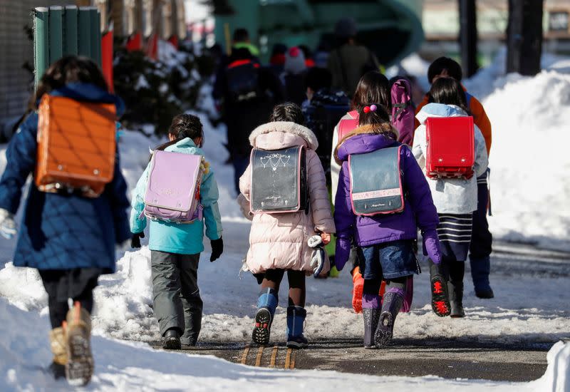 FILE PHOTO: Elementary school students walk on snow-covered street in Hokkaido, where the governor declared a state of emergency