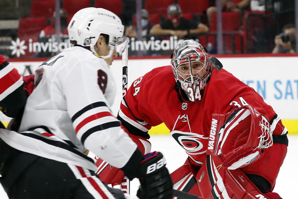 Carolina Hurricanes goaltender Petr Mrazek (34) tries to snare the puck in front of a charging Chicago Blackhawks' Dominik Kubalik (8) during the first period of an NHL hockey game in Raleigh, N.C., Thursday, May 6, 2021. (AP Photo/Karl B DeBlaker)