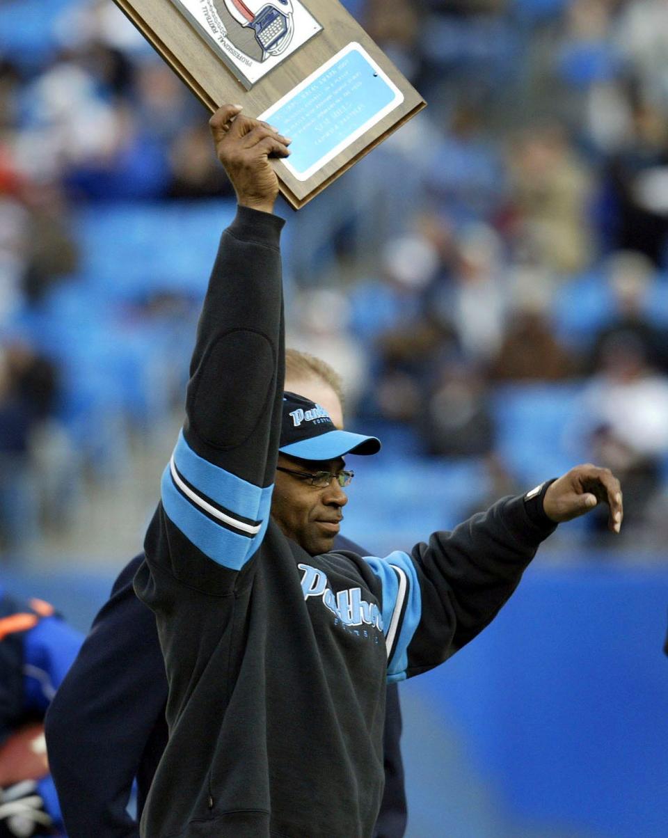 Panthers linebackers coach Sam Mills receives the George Halas award from the Professional Football Writers Association as the coach or player who has overcome an injury or personal problems before the teams' game in Charlotte, N.C., Dec. 12, 2004.