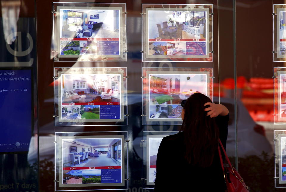 A woman reacts as she looks at houses for sale on display in the window of a real estate agency. (Credit:  David Gray, REUTERS)