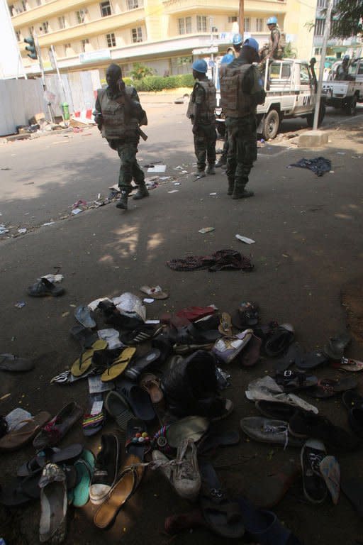 UN peacekeepers on a street in Abidjan as shoes are seen on the pavement at the scene of a stampede, on January 1, 2013. At least 60 people died and at least dozens were injured as crowds stampeded overnight during celebratory New Year's fireworks, Ivory Coast rescue workers said on January 1, 2013