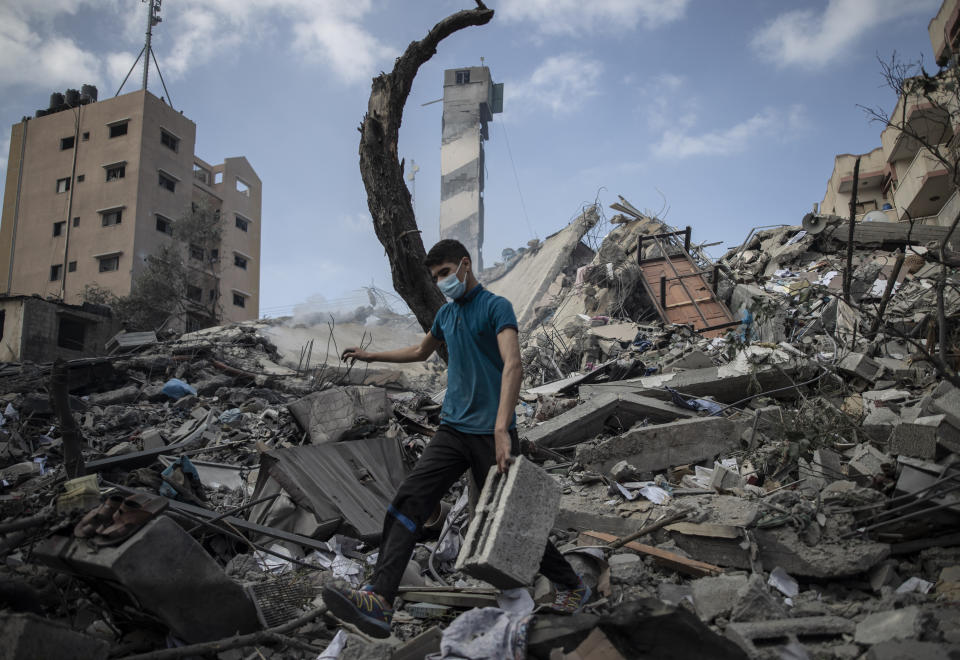 A Palestinian man inspects the damage of a six-story building which was destroyed by an early morning Israeli airstrike, in Gaza City, Tuesday, May 18, 2021. Israel carried out a wave of airstrikes on what it said were militant targets in Gaza, leveling a six-story building in downtown Gaza City, and Palestinian militants fired dozens of rockets into Israel early Tuesday, the latest in the fourth war between the two sides, now in its second week. (AP Photo/Khalil Hamra)