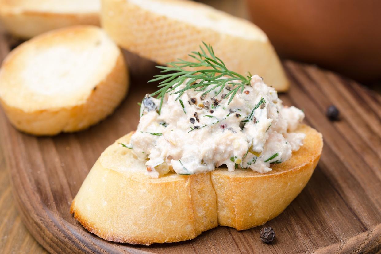 Closeup of smoked mackerel pate with griddled toast and cress salad on a piece of French bread, selective focus, on a wooden board with three more slices blurred in the background