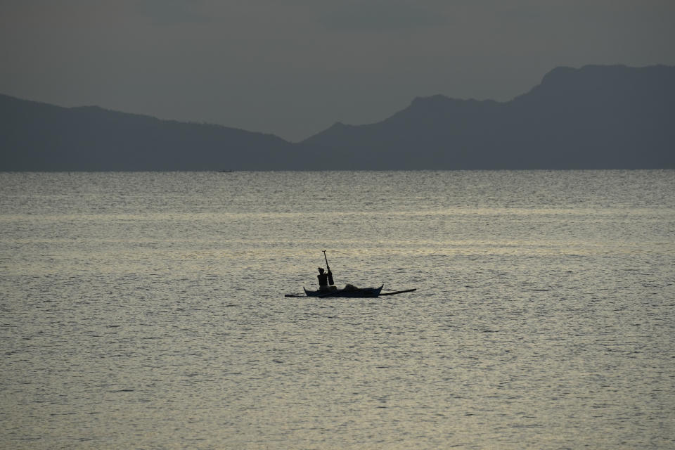 A fisherman works at sea in Legaspi, Albay province, northeastern Philippines, Sunday, June 11, 2023. Thousands of villagers have been forced to leave rural communities within a 6-kilometer radius of Mayon volcano's crater in Albay province. (AP Photo/Aaron Favila)