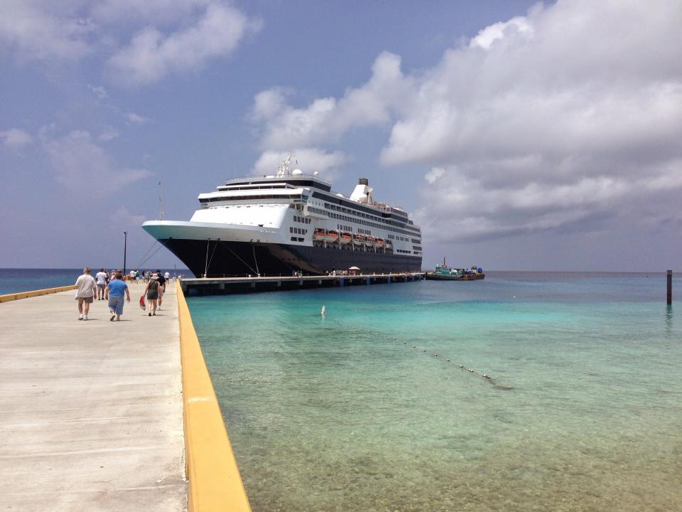 A group of people walking along a concrete dock toward Victoria Cruises Line's residential cruise ship.