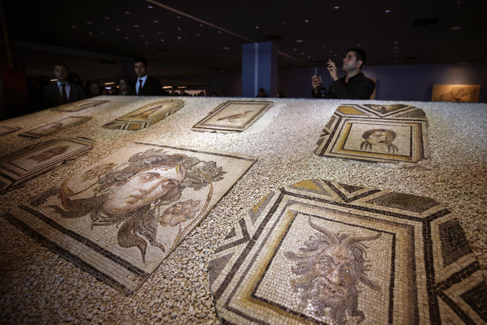 Visitors walk next to Roman-era mosaics that were part of a U.S. university's art collection and were returned to Turkey, more than half a century after looters smuggled them out, during an exhibition at the Zeugma Mosaic Museum, in Gaziantep, Turkey, Saturday, Dec. 8, 2018. Ohio's Bowling Green State University bought the 12 mosaics from a New York gallery in 1965. Turkish and Bowling Green officials agreed to their return in May 2018. (AP Photo/Emrah Gurel)