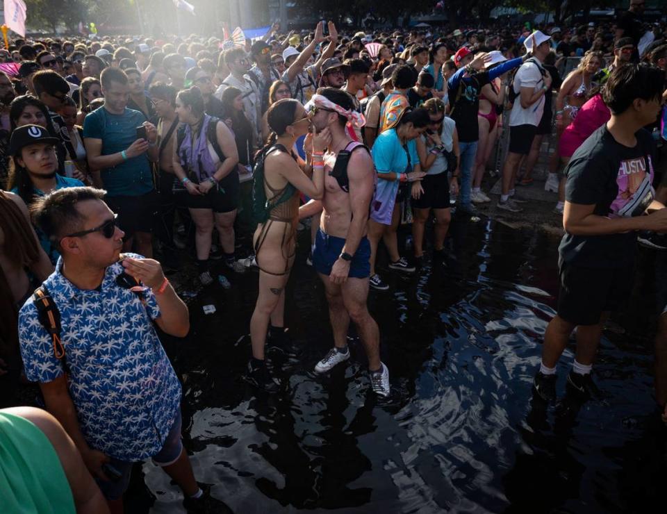 Two festivalgoers kiss while standing in a puddle of water left over from the previous days rain during Ultra day 3 on Sunday, March 24, 2024, at Bayfront Park in downtown Miami.