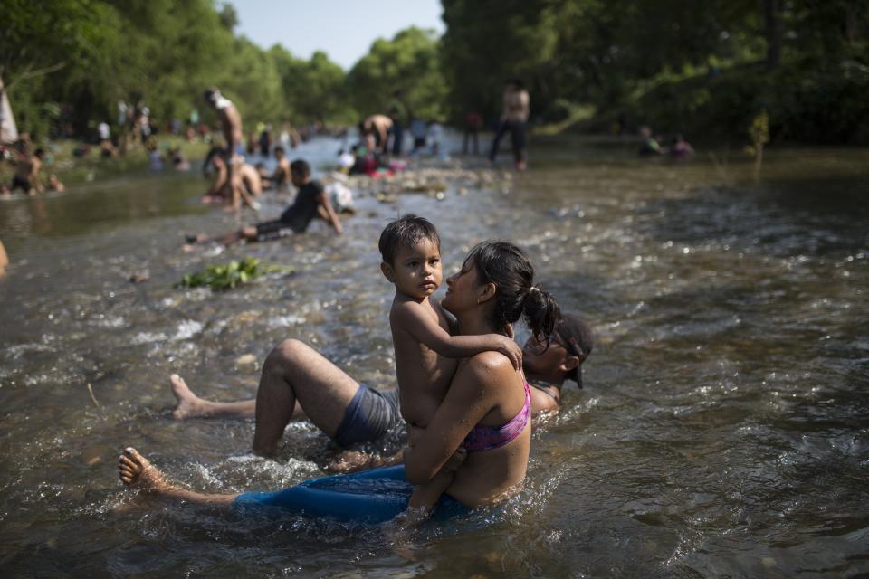 Lenny embraces her son Steven, 1, while bathing after walking with a Central American caravan of migrants in Tapanatepec, Mexico, Saturday, Oct. 27, 2018. On Saturday, more than a hundred federal police dressed in riot gear blocked a rural highway in southern Mexico shortly before dawn to encourage the migrants to apply for refugee status in Mexico rather than continuing the long, arduous journey north. (AP Photo/Rodrigo Abd)