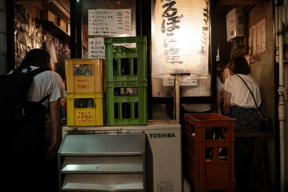 A woman, left, peeks into a packed izakaya-style restaurant at the Golden Gai in the Shinjuku district of Tokyo, July 28, 2019. (AP Photo/Jae C. Hong)