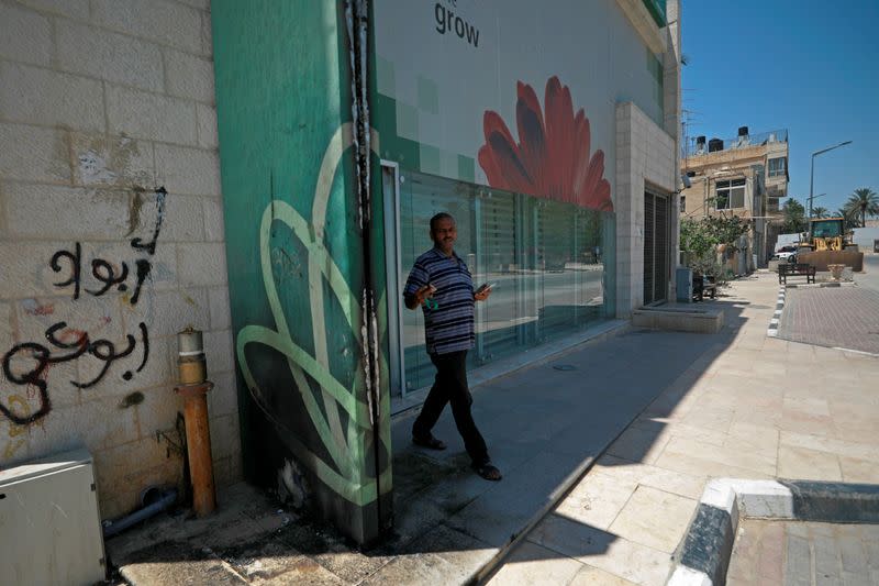 A Palestinian man walks out of the Cairo Amman Bank as a burnt part of the bank's exterior is seen, in Jericho in the Israeli-occupied West Bank