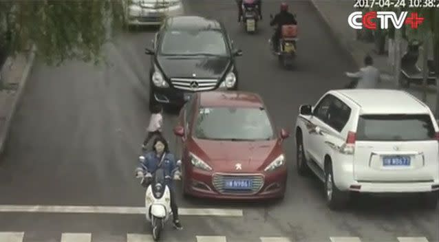 The child is seen running in between two cars which appear to be stopped before continuing across the road. Source: CCTV+/ YouTube