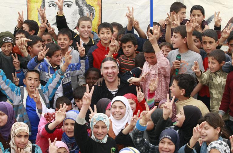 Syrian actor-turned-director Nawwar Bulbul (C) poses for a group photo with refugee children outside 'Shakespeare tent', after rehearsing King Lear, at the sprawling Zaatari refugee camp in Jordanian desert near the border with Syria, on March 8, 2014