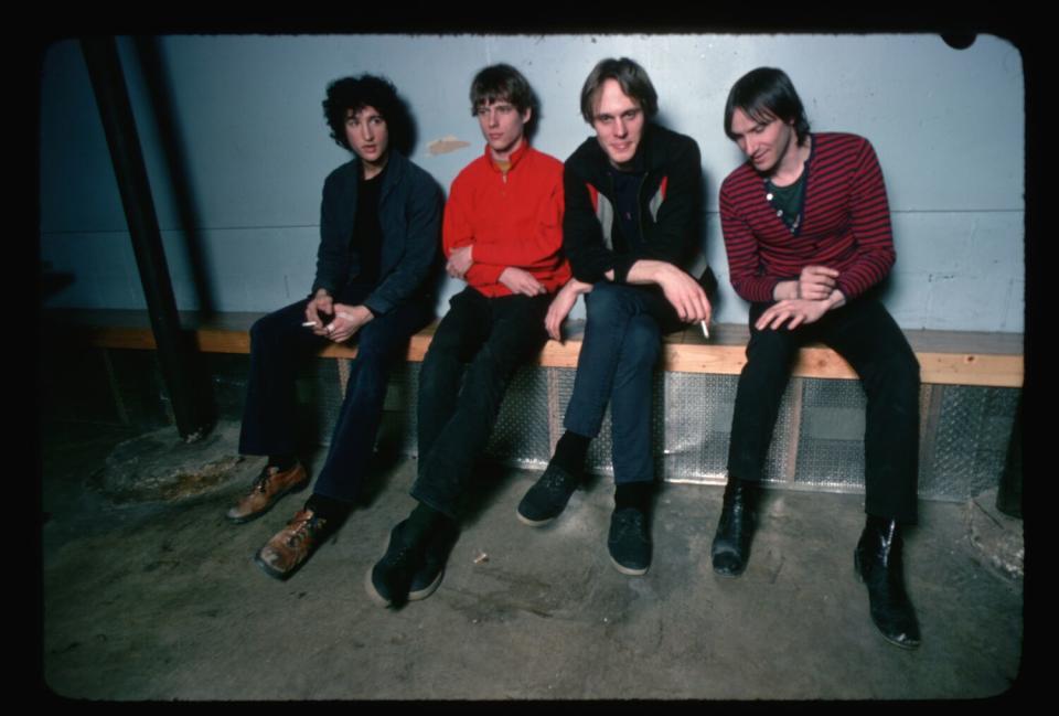 Four guys in a rock band seated on a bench