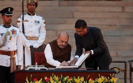 Amit Shah signs documents after taking his oath as a cabinet minister during a swearing-in ceremony at the presidential palace in New Delhi