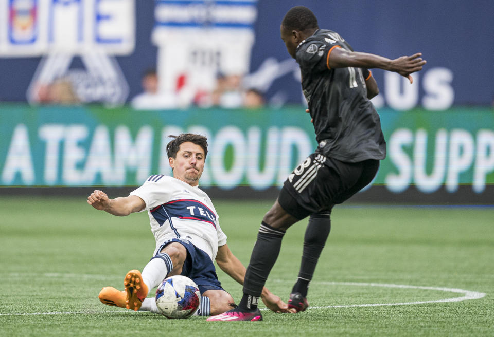 Vancouver Whitecaps' Alessandro Schopf, left, slides to take the ball away from Houston Dynamo's Ibrahim Aliyu during the first half of an MLS soccer match Wednesday, May 31, 2023, in Vancouver, British Columbia. (Rich Lam/The Canadian Press via AP)