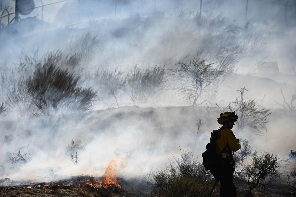 Against a backdrop of intense smoke, firefighters from Cal Fire set backfires to prevent wildfire from spreading.