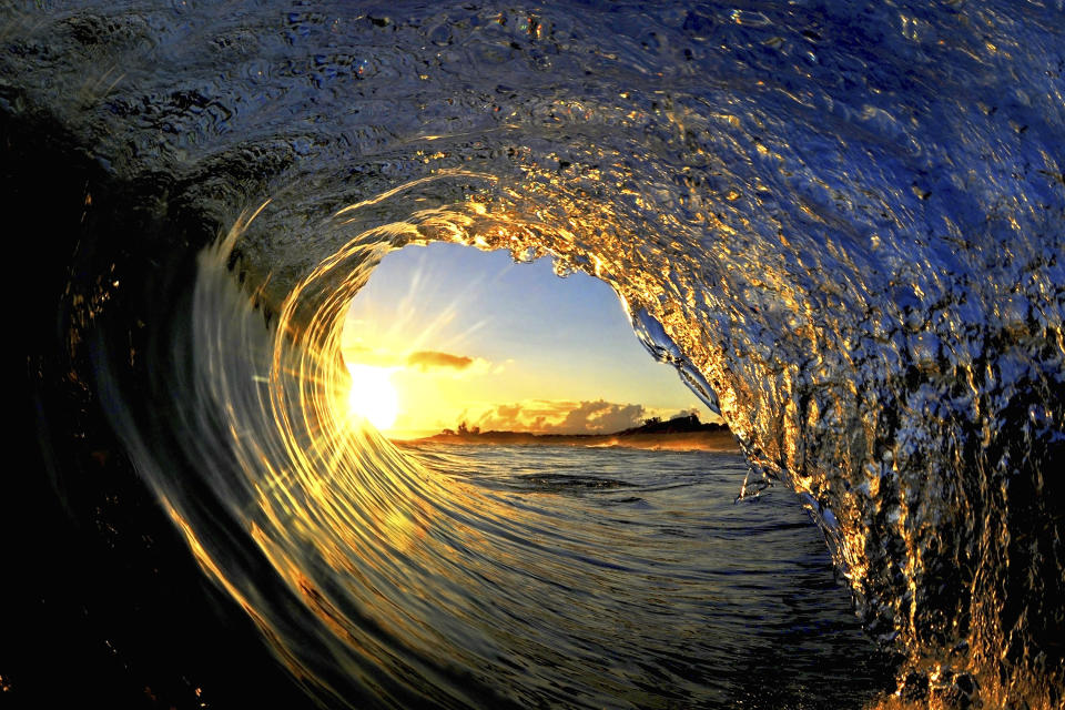 In this undated photo entitled "Sun Curl," the rising sun is framed by a breaking wave on the North Shore of Oahu near Haleiwa, Hawaii. The image appears in photographer Clark Little's new book, "The Art of Waves." (Clark Little via AP)