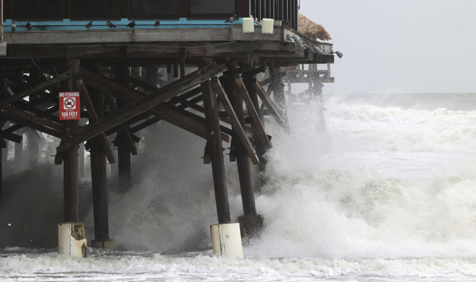 FILE - Waves break on the Cocoa Beach Pier as Tropical Storm Nicole makes its presence felt, Nov. 9, 2022, in Cocoa Beach, Fla. The Biden administration on Thursday, April 11, 2024, awarded $830 million in grants to fund 80 projects aimed at toughening the nation's aging infrastructure against the harmful impacts of climate change. (Ricardo Ramirez/Orlando Sentinel via AP, File)