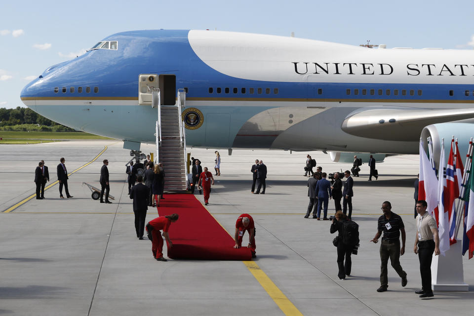 Workers unroll a red carpet