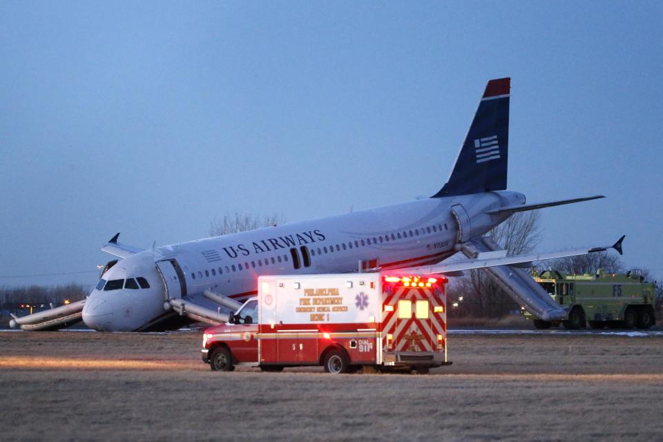 Emergency vehicles drive past a damaged US Airways jet at the end of a runway at the Philadelphia International Airport, Thursday, March 13, 2014, in Philadelphia. Airline officials said the flight was heading to Fort Lauderdale, Fla., when the pilot was forced to abort takeoff around 6:30 p.m., after the front landing gear failed. An airport spokeswoman said no injuries have been reported. (AP Photo/Matt Slocum)