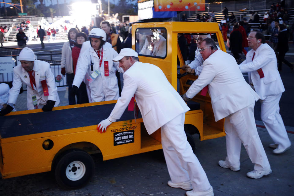 Dressed in their signature white suits, tournament members push a utility truck off the parade route in the early morning hours prior to the start of the 124th Rose Parade in Pasadena, Calif., Tuesday, Jan. 1, 2013. (AP Photo/Patrick T. Fallon)