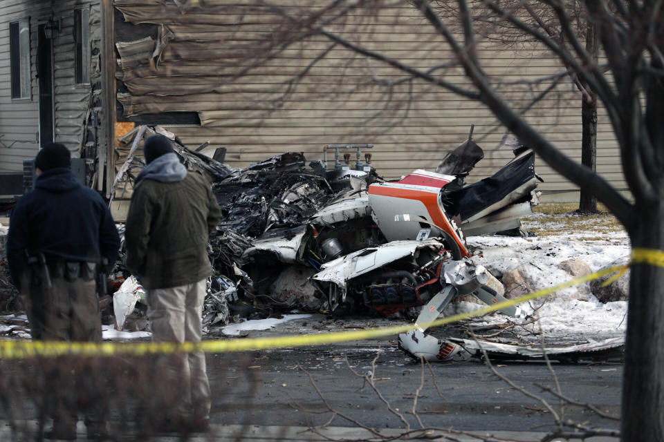 People look at the debris from a small private plane that crashed in a residential area Wednesday, Jan. 15, 2020, in Roy, Utah. The small plane crashed Wednesday, killing the pilot as the aircraft narrowly avoided hitting any townhomes, authorities said. (Ben Dorger/Standard-Examiner, via AP)