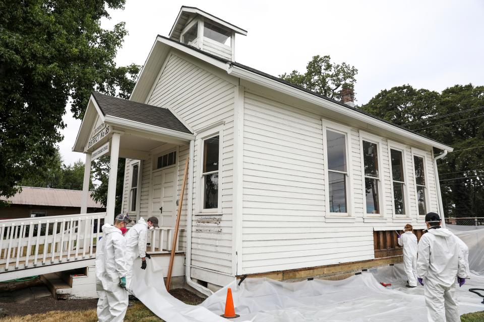 Students from the Historic Preservation and Restoration program at Clatsop Community College work to repair siding on the historical Criterion Schoolhouse.