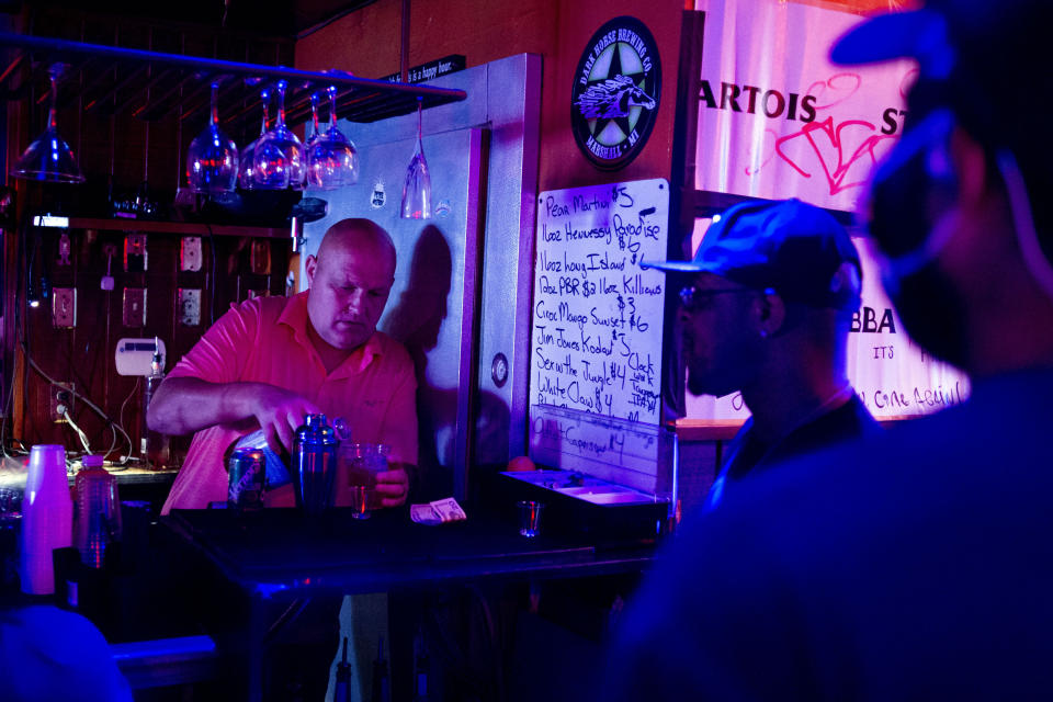 FILE - In this June 8, 2020, file photo, Rodney Ott, owner of The Loft, makes mixed drinks from behind the bar for patrons as he reopens fully for the first time amid the coronavirus outbreak in downtown Flint, Mich. Authorities are closing honky tonks, bars and other drinking establishments in some parts of the U.S. to stem the surge of COVID-19 infections — a move backed by sound science about risk factors that go beyond wearing or not wearing masks. (Jake May/The Flint Journal via AP, File)