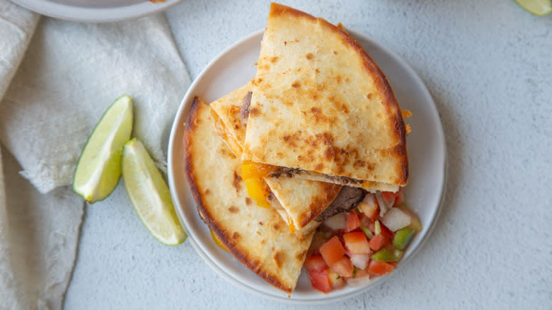 sliced steak quesadillas on white plate with lime