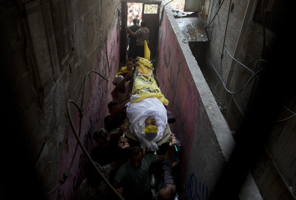 Palestinian carry the body of Mohammed Abbas, 21, who was killed by Israeli troops during Friday's protest at the Gaza Strip's border with Israel, into the family home during his funeral in Gaza City, Saturday, Oct. 13, 2018. (AP Photo/Khalil Hamra)