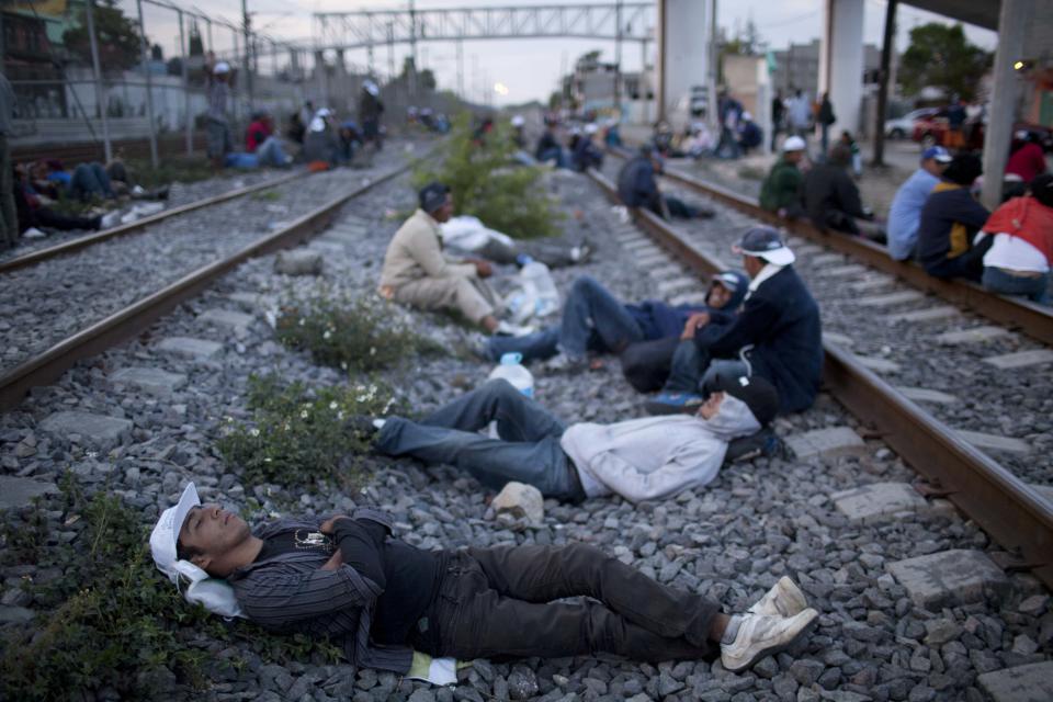 In this May 17, 2012 photo, migrants, mostly from Honduras, rest on railroad tracks as they wait for a train headed north, in Lecheria, on the outskirts of Mexico City. While the number of Mexicans heading to the U.S. has dropped dramatically, a surge of Central American migrants is making the 1,000-mile northbound journey this year, fueled in large part by the rising violence brought by the spread of Mexican drug cartels. (AP Photo/Alexandre Meneghini)