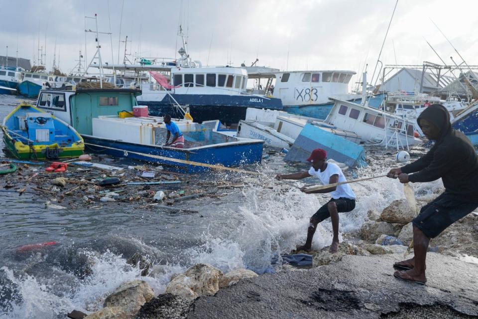 <p>Fishermen pull a boat damaged by Hurricane Beryl back to the dock at the Bridgetown Fisheries in Barbados</p> (AP)