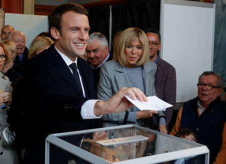 Emmanuel Macron (L), head of the political movement En Marche !, or Onwards !, and candidate for the 2017 French presidential election, casts his ballot in the first round of 2017 French presidential election at a polling station in Le Touquet, northern France, April 23, 2017. REUTERS/Philippe Wojazer