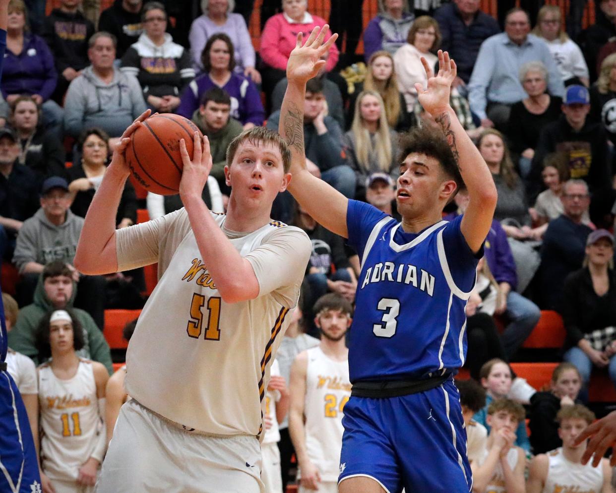 Onsted's Ayden Davis handles the ball while defended by Adrian's Joe Francis during a game last season. The 6-10 Davis is one of many returning boys basketball stars in Lenawee County this season.