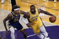 Los Angeles Lakers' LeBron James, right, dribbles past Golden State Warriors' Kelly Oubre Jr. during the first half of an NBA basketball game, Monday, Jan. 18, 2021, in Los Angeles. (AP Photo/Jae C. Hong)