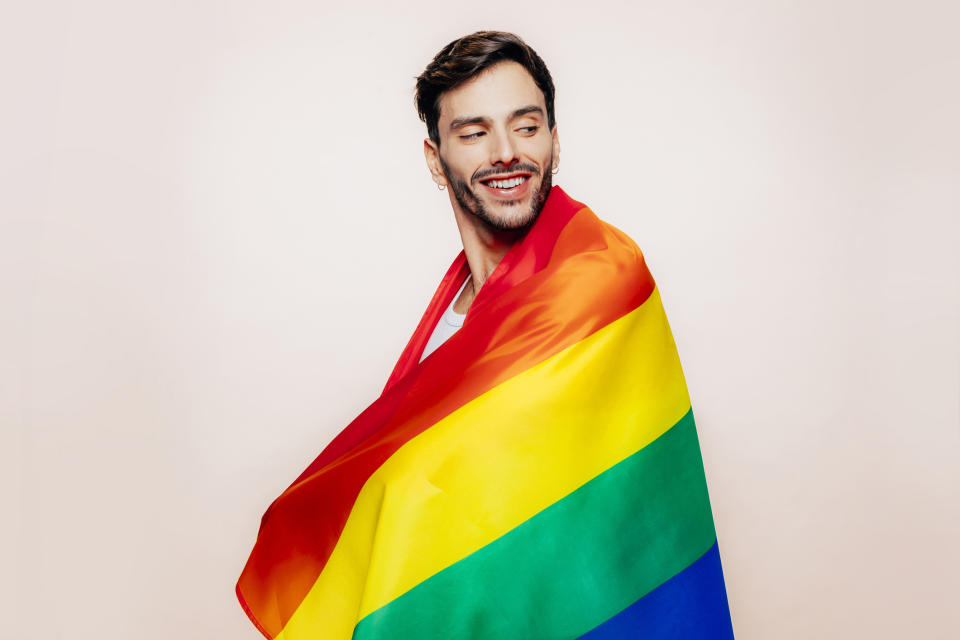 A man draped in an LGBTQ+ flag
