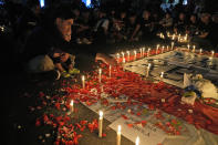 A man sprinkles flowers during a candle light vigil for the victims of Saturday's soccer riots, in Jakarta, Indonesia, Sunday, Oct. 2, 2022. Panic and a chaotic run for exits after police fired tear gas at an Indonesian soccer match in East Java to drive away fans upset with their team's loss left a large number of people dead, most of whom were trampled upon or suffocated. (AP Photo/Dita Alangkara)