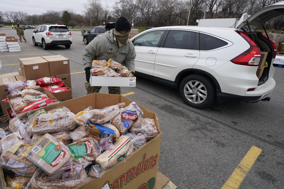 Corpl. James Bates carries a box of groceries to a car at a food bank distribution by the Greater Cleveland Food Bank, Thursday, Jan. 7, 2021, in Cleveland. (AP Photo/Tony Dejak)