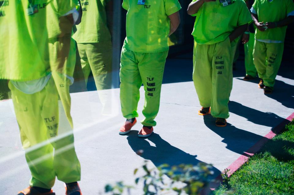 Men wearing neon-colored jail clothes signifying immigration detainees walk to pick up their lunches at the Theo Lacy Facility, a county jail which houses convicted criminals as well as immigration detainees, March 14, 2017 in Orange, California, about 32 miles (52km) southeast of Los Angeles.US President Donald Trumps first budget provides more than USD 4.5 billion in new spending to fight illegal immigration by adding immigration and border enforcement agents, prosecutors and judges, as well as building a wall on the border with Mexico. / AFP PHOTO / Robyn Beck        (Photo credit should read ROBYN BECK/AFP/Getty Images)