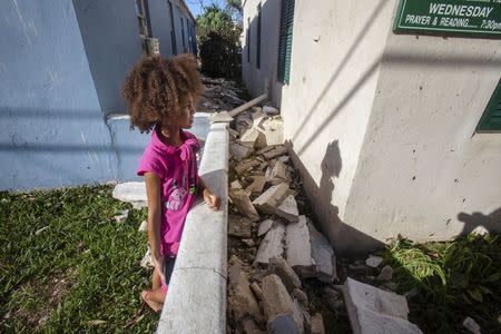 A girl views fallen pieces of a church roof after Hurricane Gonzalo passed through in Sandys Parish, western Bermuda, October 18, 2014. REUTERS/Nicola Muirhead