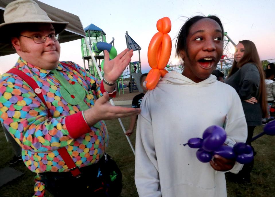 Taylor Donaldson, 15, right, reacts as balloon artist Justin Reed places a balloon parrot on her shoulder after Reed created the balloon animal for her during the National Night Out in La Vergne, on Tuesday, Oct. 4, 2022, at Veterans Memorial Park.