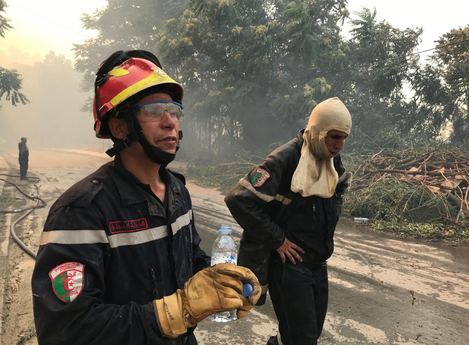 Firefighters stand along a road during a forest fire in Ain al-Hammam village in the Tizi Ouzou region, east of Algiers, Algeria August 10, 2021. REUTERS/Abdelaziz Boumzar